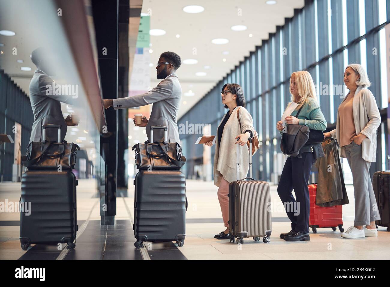 Vue latérale horizontale des personnes se tenant en file d'attente avec leurs bagages au comptoir d'enregistrement de l'aéroport, espace de copie Banque D'Images