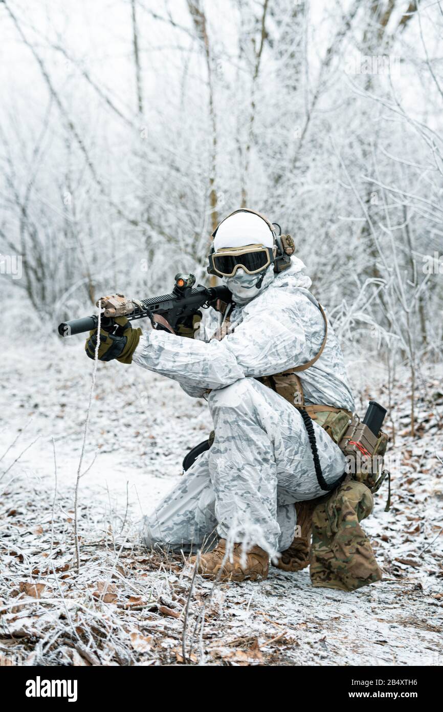 Airsoft homme en tenue de camouflage blanche avec machinegun. Un soldat  avec muchinegun s'est levé sur des genoux dans la forêt d'hiver. Photo  verticale, vue latérale Photo Stock - Alamy