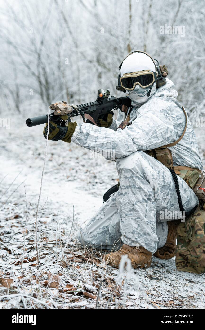 Airsoft homme en tenue de camouflage blanche avec machinegun. Un soldat  avec muchinegun s'est levé sur des genoux dans la forêt d'hiver. Vue  latérale Photo Stock - Alamy