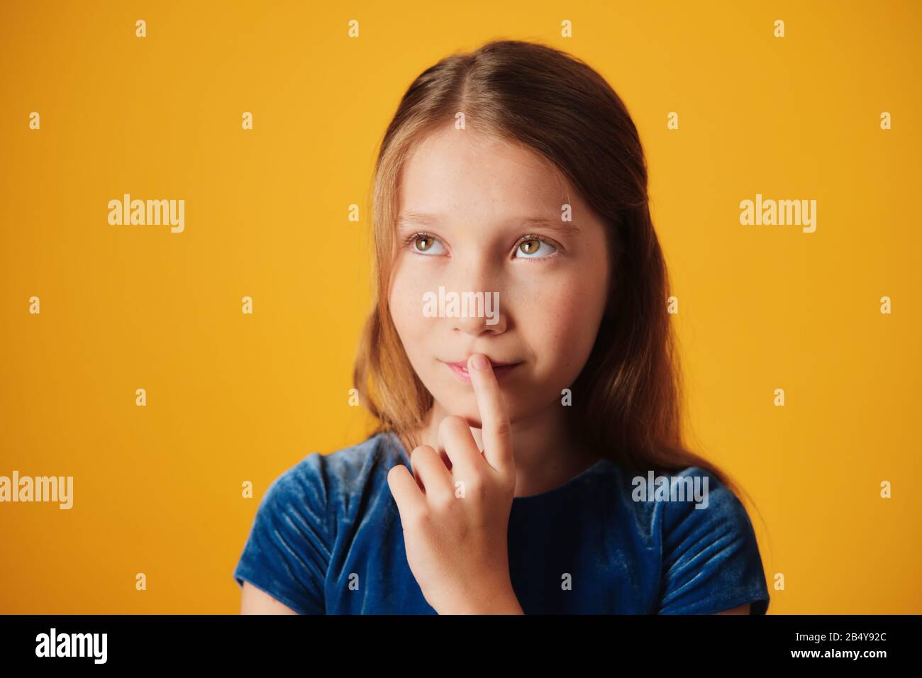 Rêvant De Jour Petite Fille Touchant La Bouche Et Regardant Vers Le Haut Banque D'Images