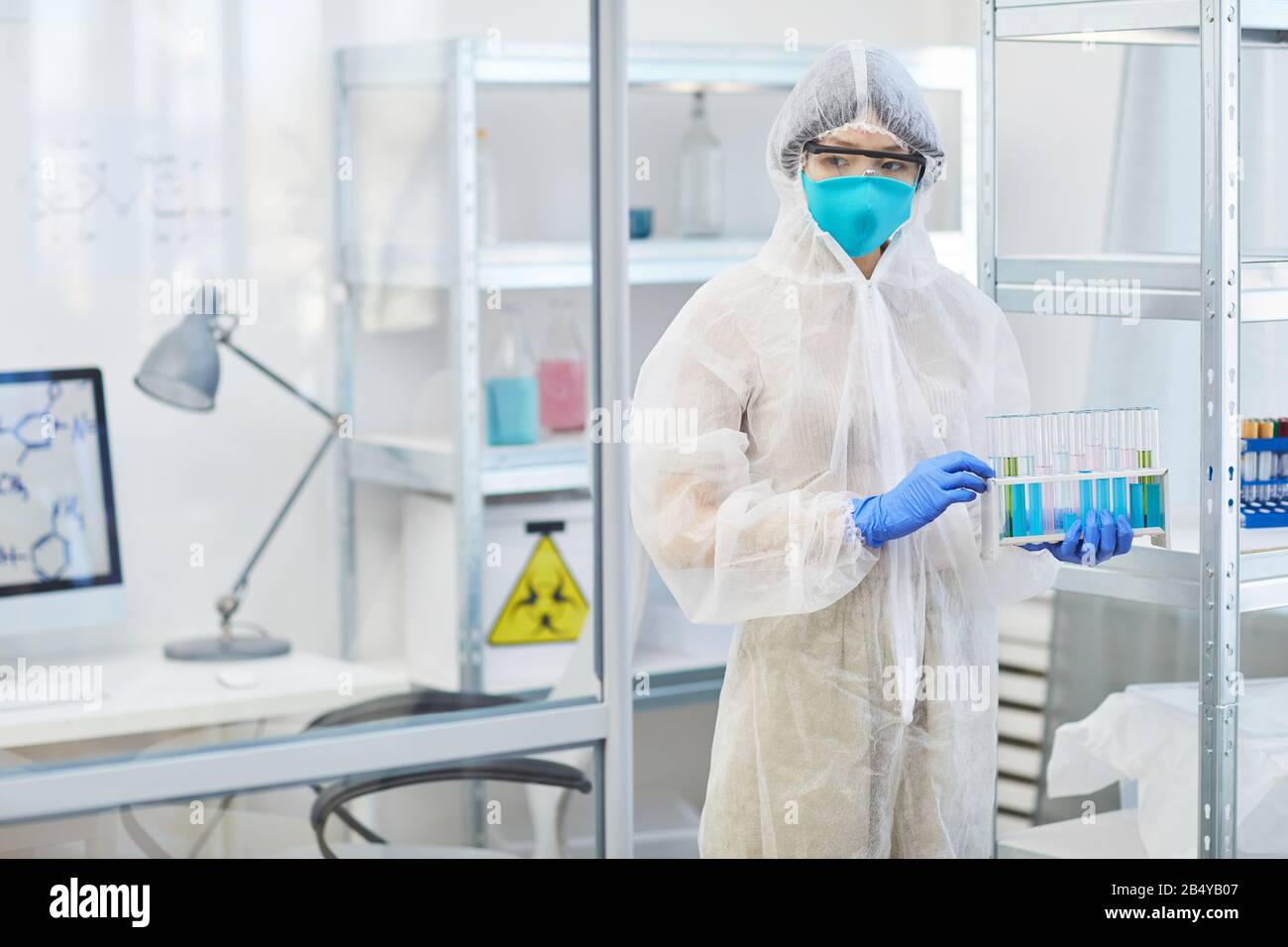 Un professionnel médical féminin non reconnaissable portant des tubes à essai de protection uniformes avec des liquides, une prise horizontale et un espace de copie Banque D'Images