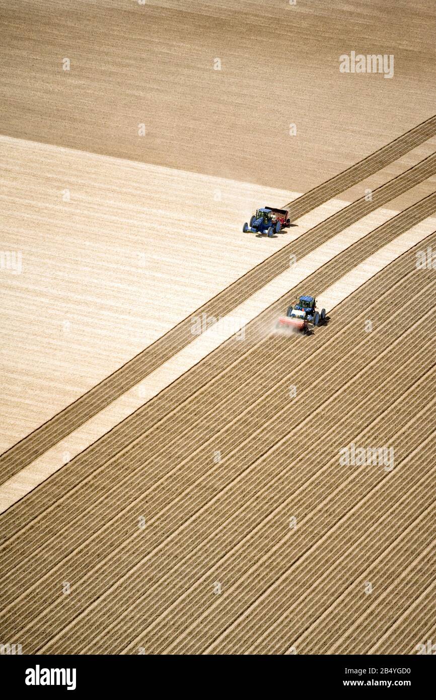 Vue aérienne de deux tracteurs travaillant dans le domaine de l'ensemencement. Une excellente image d'arrière-plan avec beaucoup de zone à copier. Banque D'Images