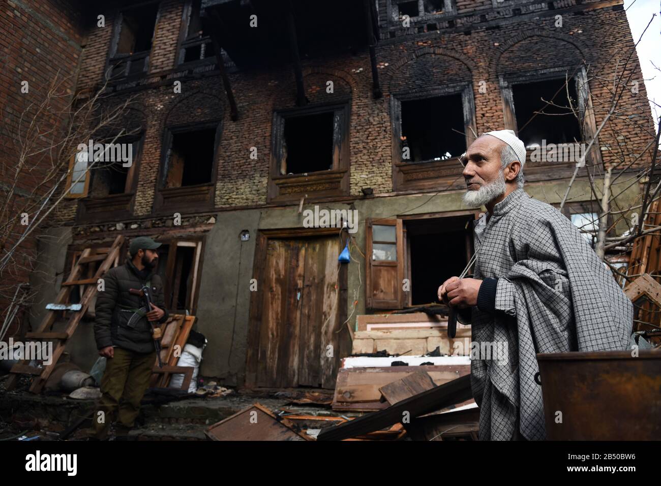 L'homme de Kashmiri et le personnel de police se tenant à l'extérieur de la maison blazée au lendemain.un couple et leur fille de trois ans ont été charmés à mort dans un blaze qui a éclaté dans la région de Khanyar de Srinagar, les responsables disent que l'incendie a éclaté d'une maison résidentielle dans la nuit. La police a entamé une enquête sur la question et une affaire a également été enregistrée. Banque D'Images