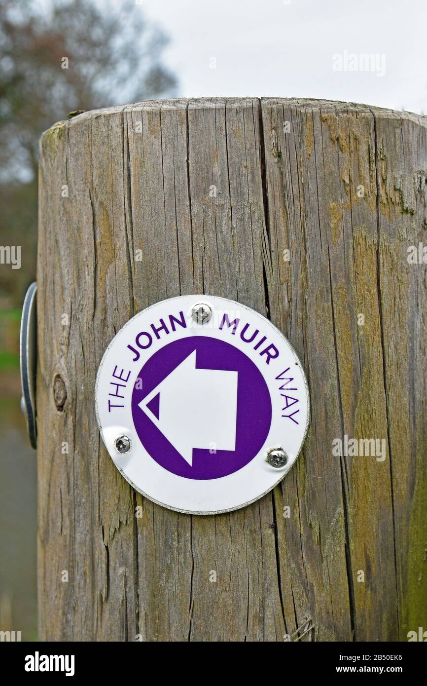 Signe pour la John Muir Way, un sentier de randonnée longue distance en Ecosse. Sur une borne en bois avec un arrière-plan flou Banque D'Images