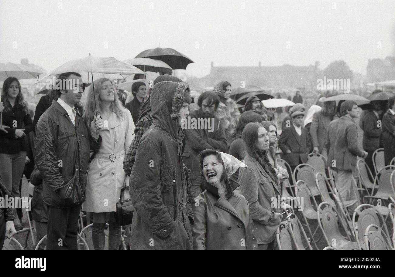 années 1970, historique, sur un jour humide, bruyant, spectateurs, quelques parapluies, s'amuser debout un concert de musique en plein air, Angleterre, Royaume-Uni. Banque D'Images années 1970, historique, sur un jour humide, bruyant, spectateurs, quelques parapluies, s'amuser debout un concert de musique en plein air, Angleterre, Royaume-Uni. Banque D'Images