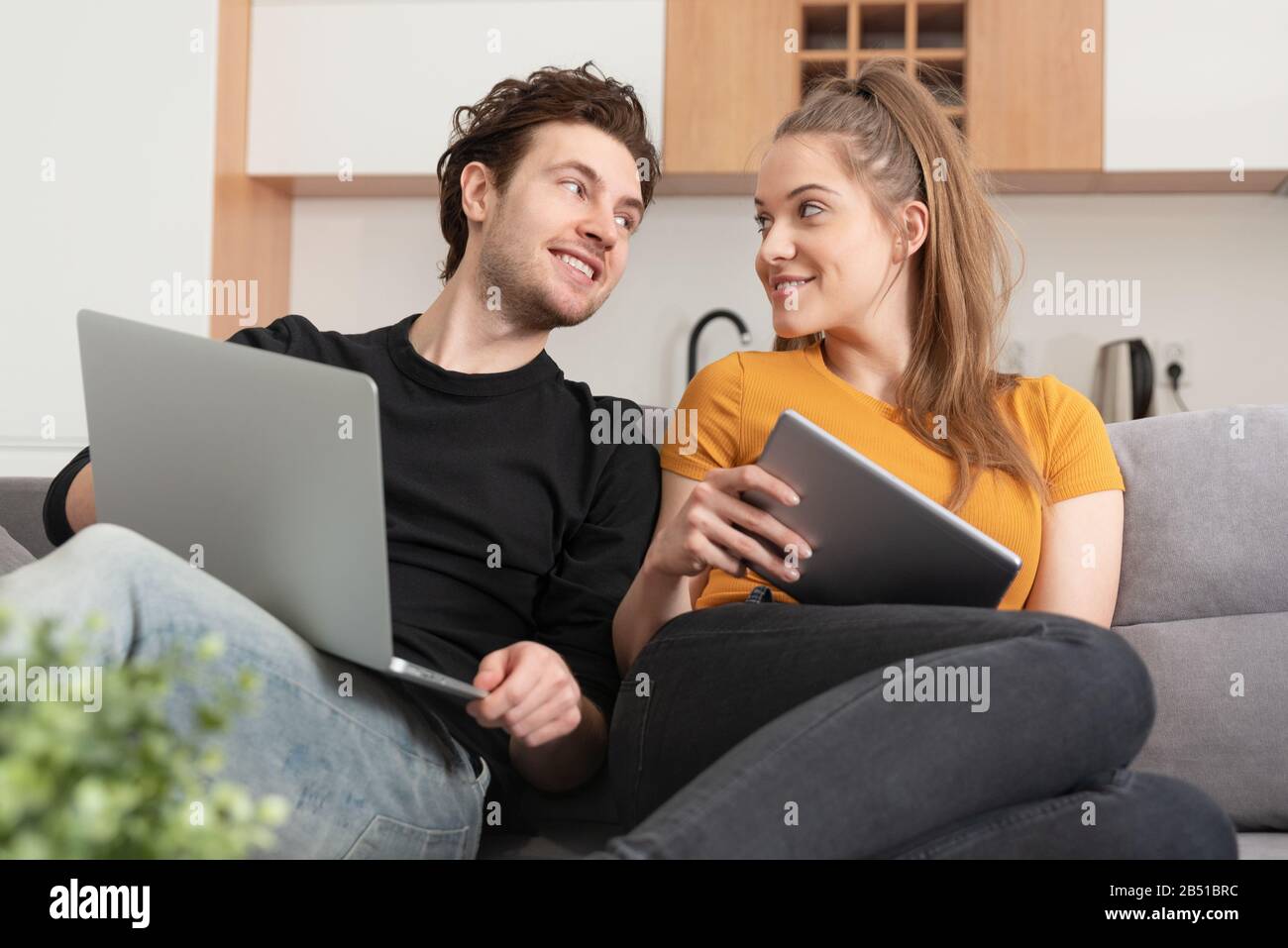 Couple utilisant Internet à domicile rapide avec ordinateur portable et tablette numérique. Femme et homme sur canapé dans le salon Banque D'Images