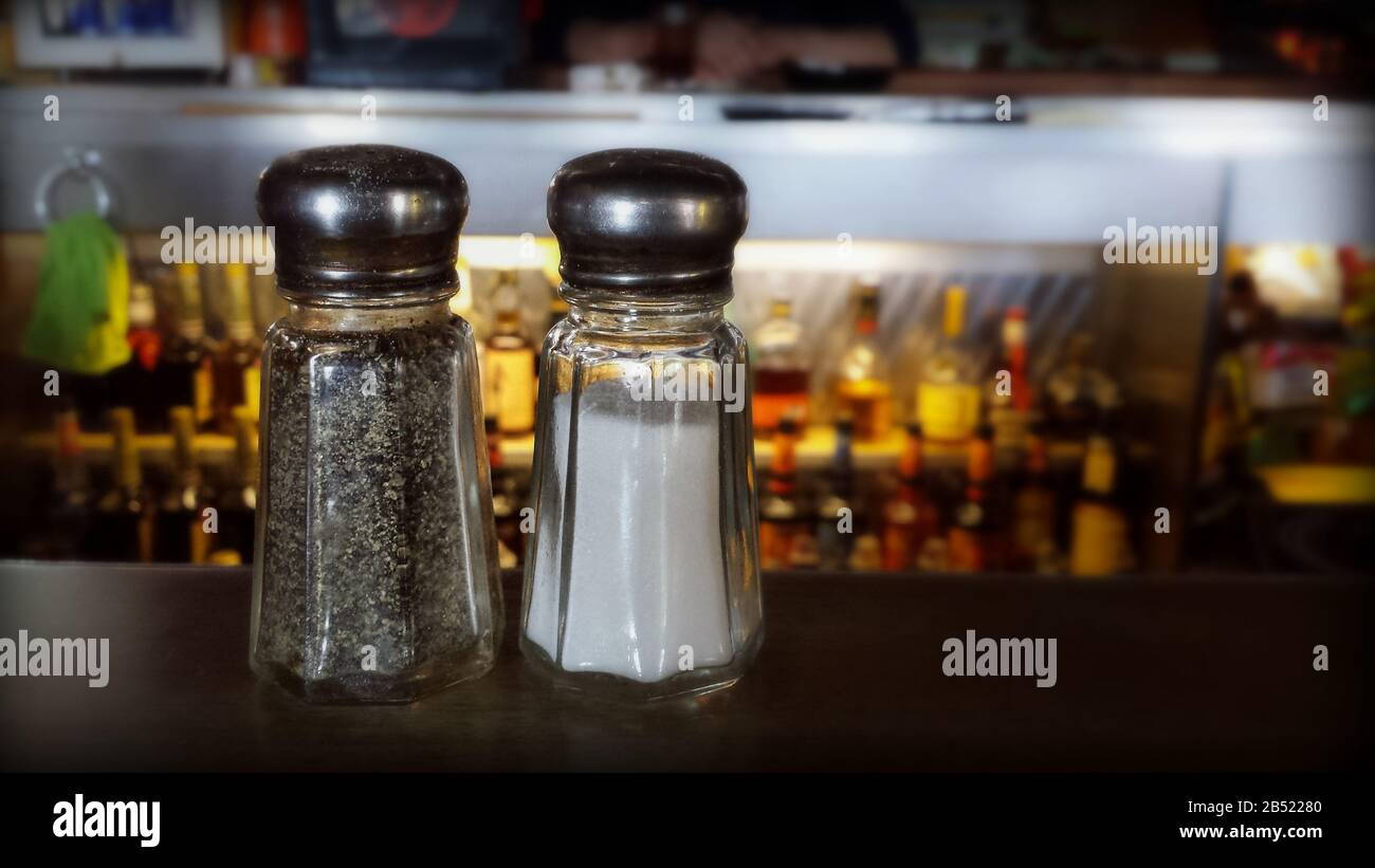 Saler et poivrer dans un bar dans une taverne locale avec des bouteilles de liqueur floues en arrière-plan Banque D'Images