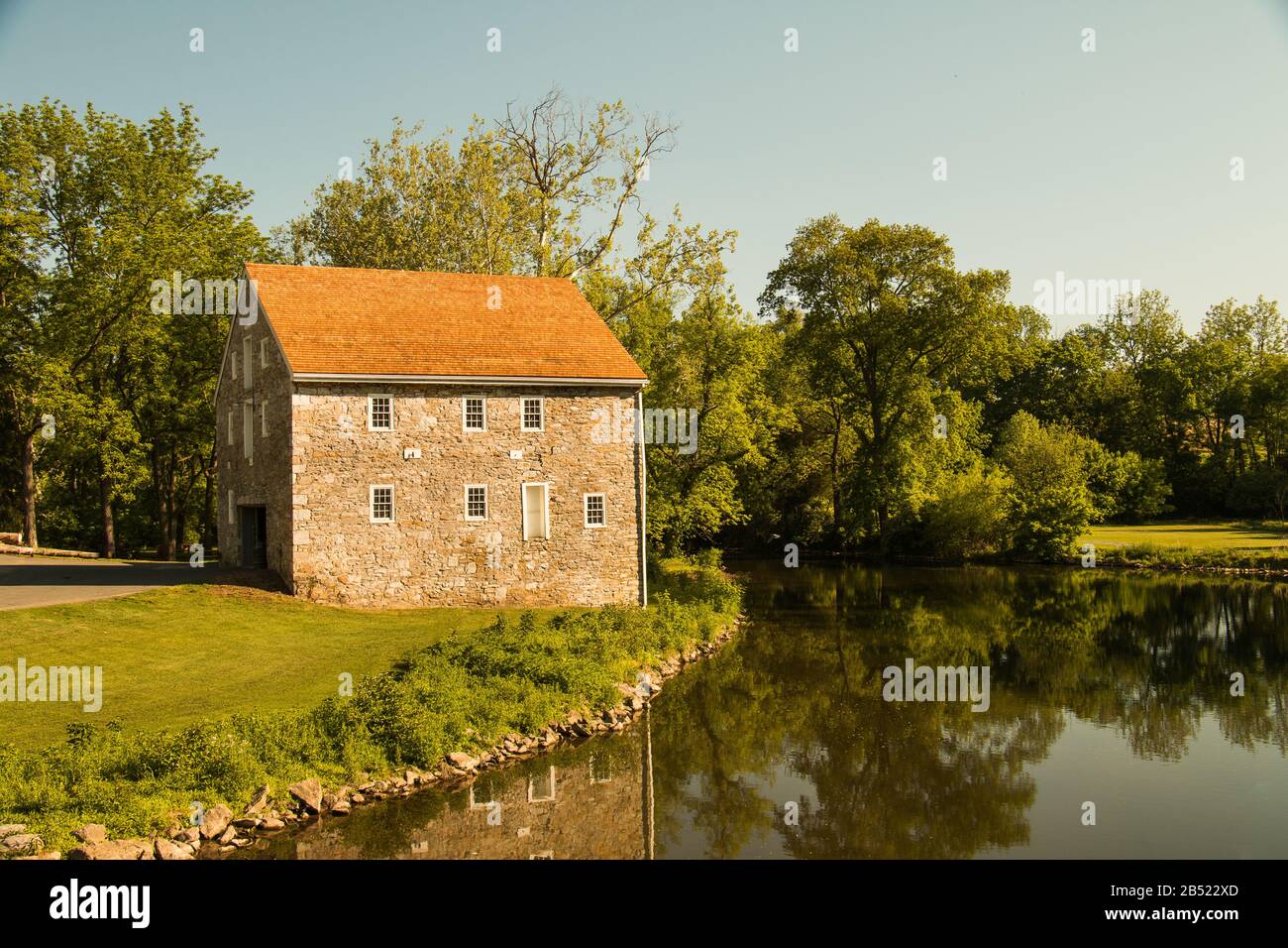 Ancienne maison en pierre à côté d'un ruisseau sinueux bordé d'arbres dans l'est de la Pennsylvanie, une journée d'été Banque D'Images