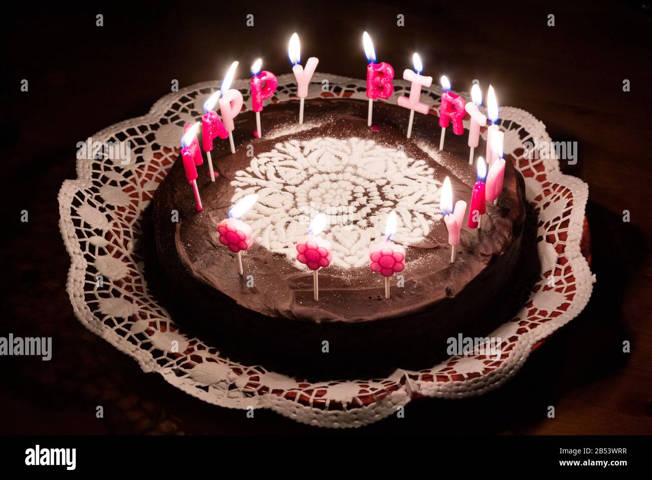 Brûlez une bonne lettre d'anniversaire bougies sur gâteau au chocolat décoré avec le sucre rangoli gros plan Banque D'Images