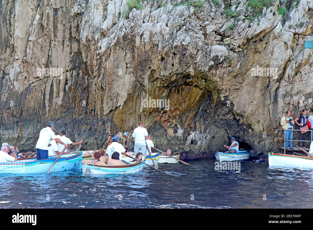 Touristes en petits bateaux attendant d'entrer dans la célèbre Grotte bleue sur l'île de Capri. Les conducteurs tirent les bateaux par une petite ouverture. Banque D'Images