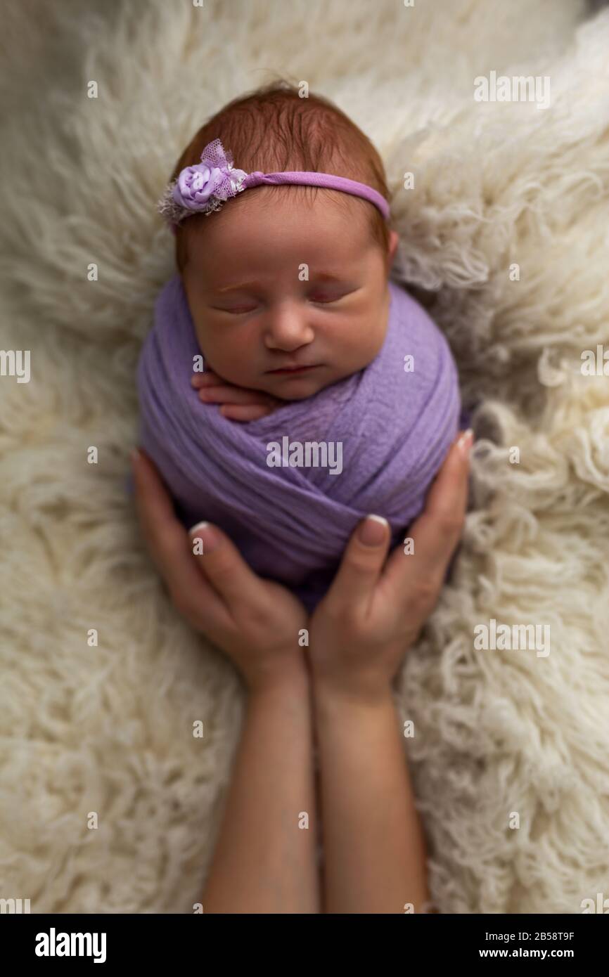 Le concept de sécurité et de bonheur. La nouvelle-fille dormait dans une posture cococoon (sac de pomme de terre) dans les bras de sa mère Banque D'Images