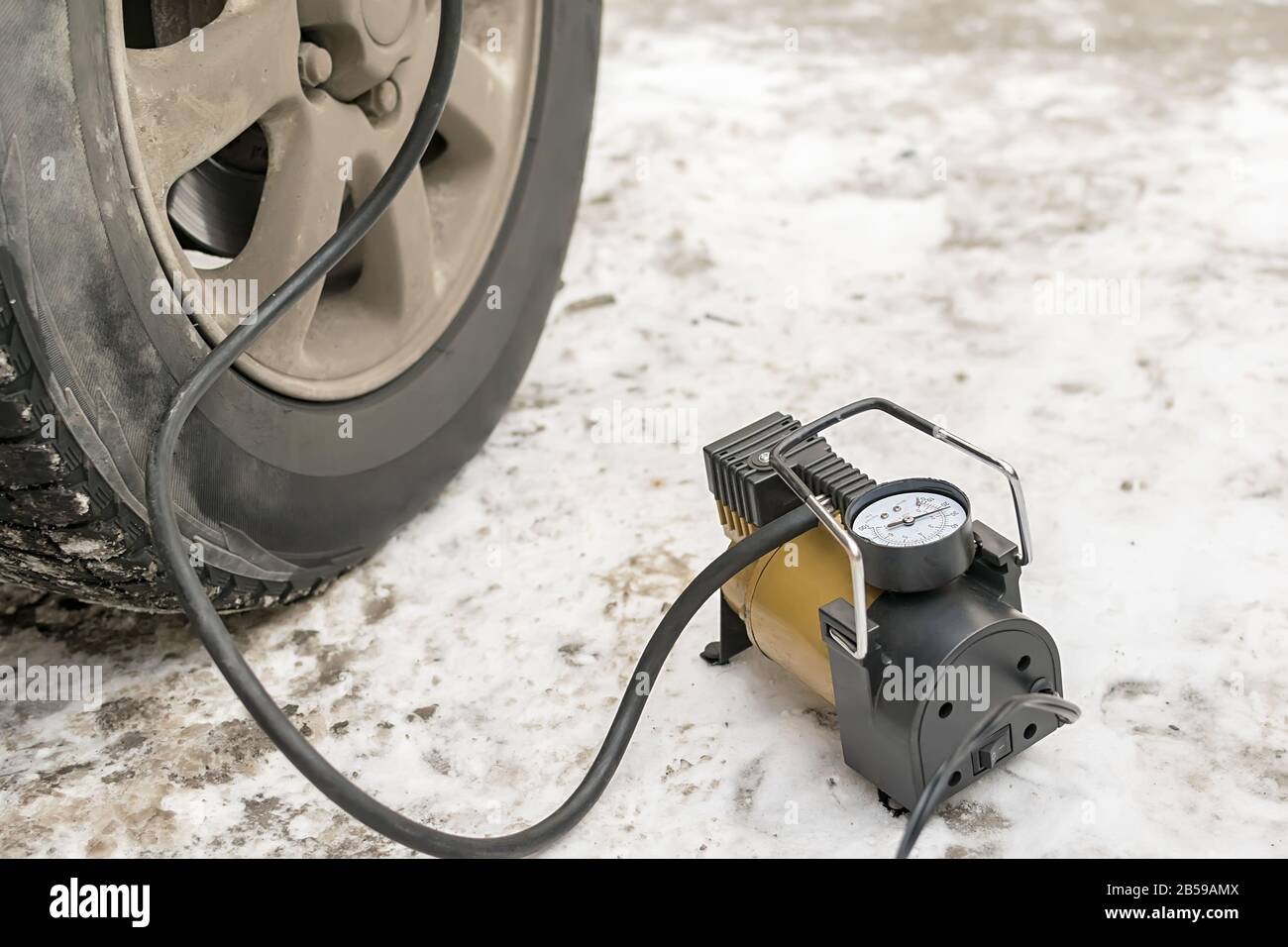 Pompe, compresseur automobile pour gonfler les pneus avec des chandelles en  hiver sur la neige et pompe le pneu plat de la voiture Photo Stock - Alamy