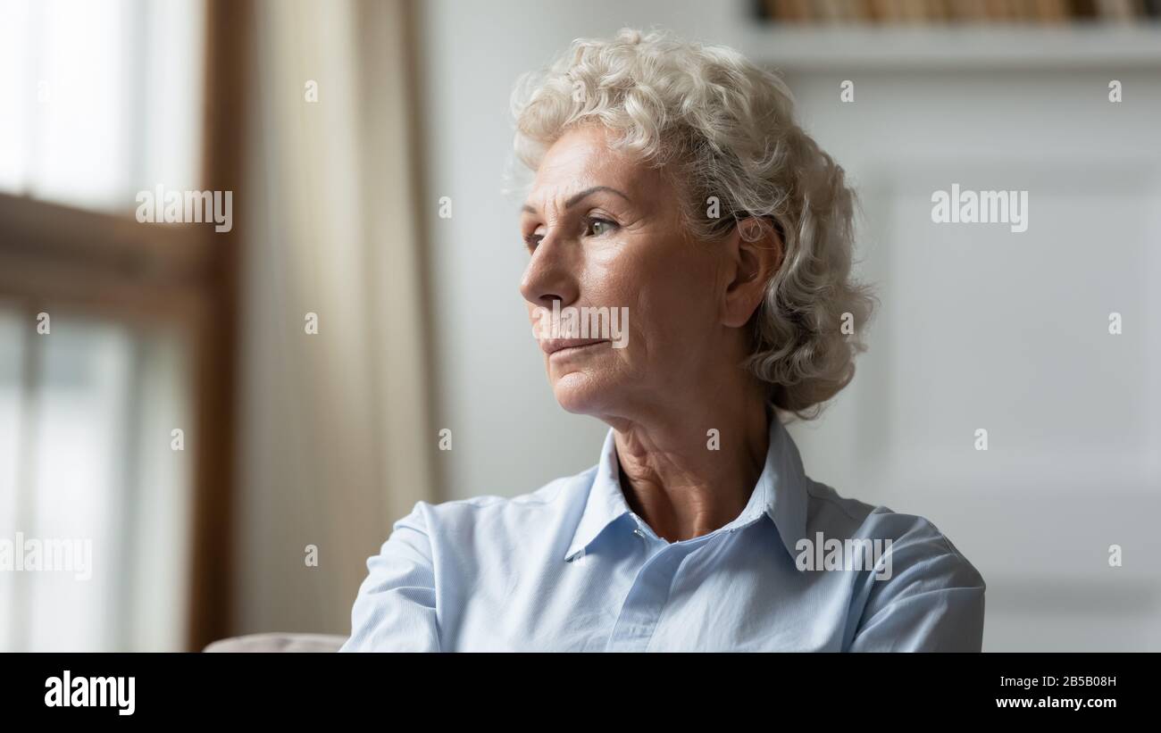 Pensive senior femme a perdu dans les pensées se sentant solitaire Banque D'Images