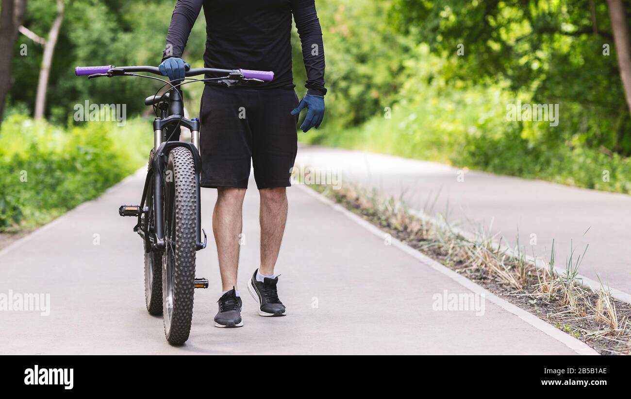 Image recadrée du cycliste qui tient le vélo dans le parc public Banque D'Images
