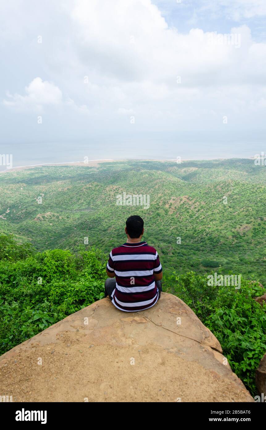Touriste masculin assis sur le bord d'un rocher, imprégnant dans la vue à Kalo Dungar, Kutch, Gujarat, Inde Banque D'Images
