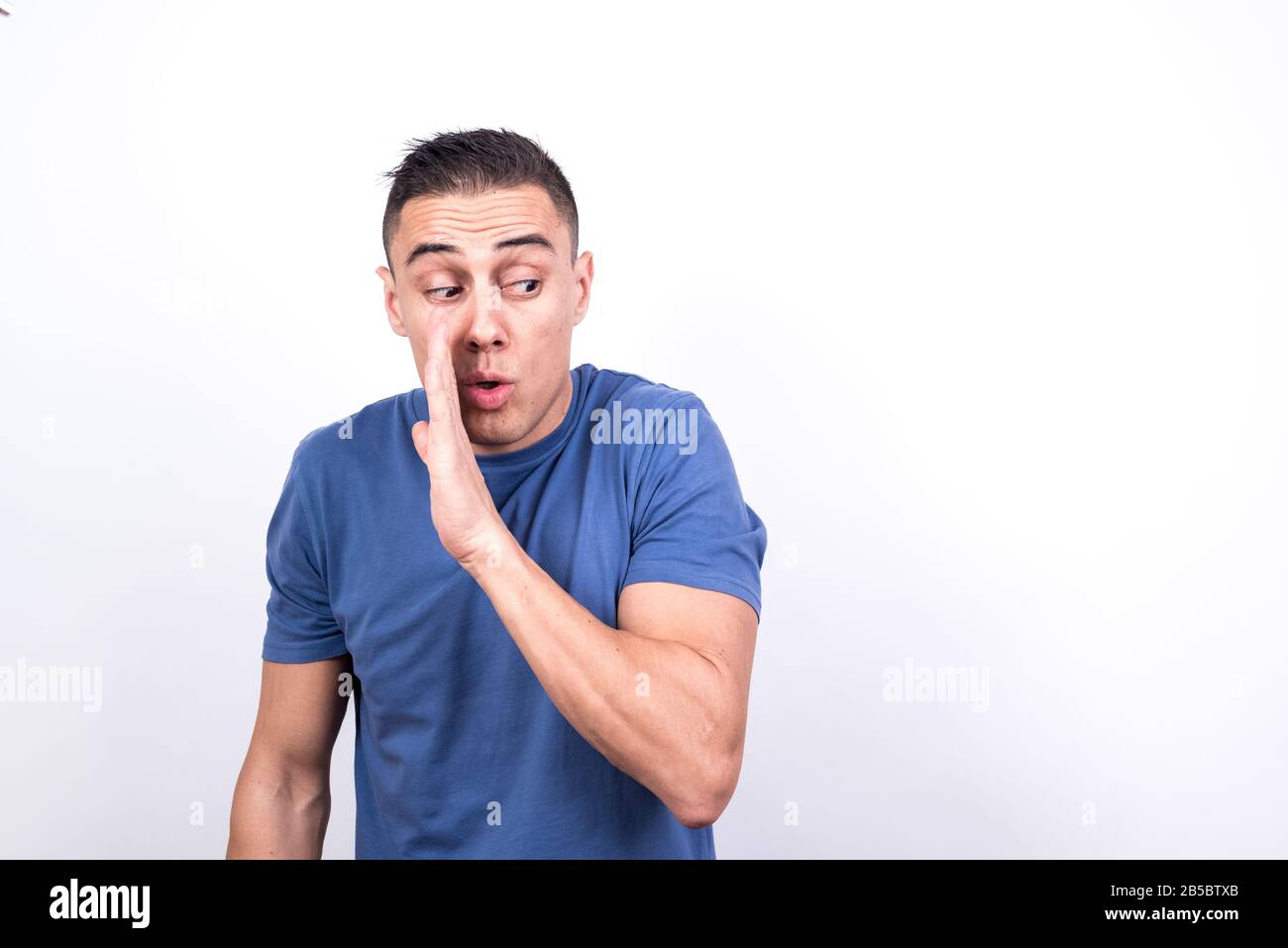 L'homme chuchote un secret, couvrant sa bouche avec sa main. Fond blanc, prise de vue moyenne Banque D'Images