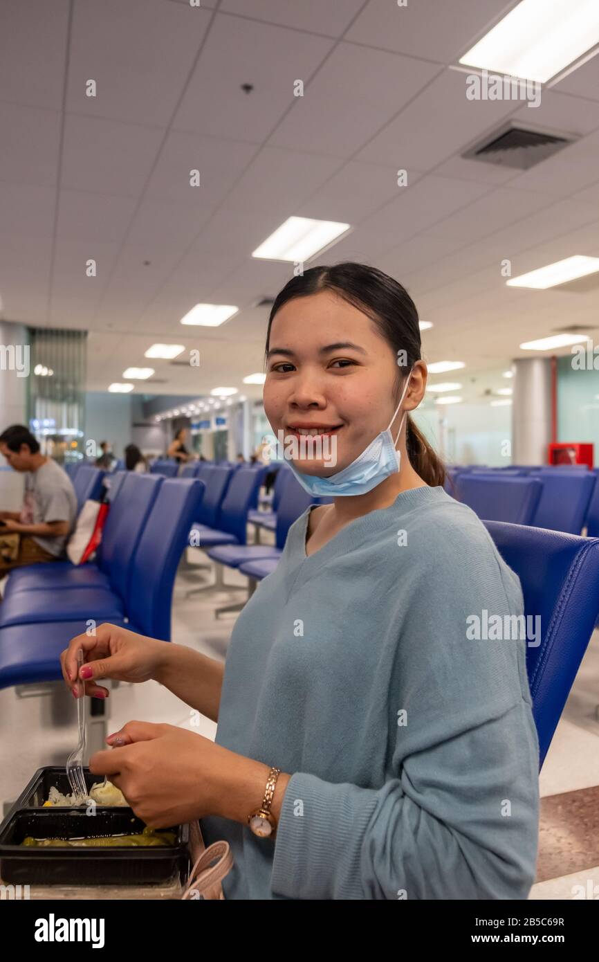 Une fille thaïlandaise mangeant de la nourriture tout en attendant de monter à bord de l'avion Banque D'Images