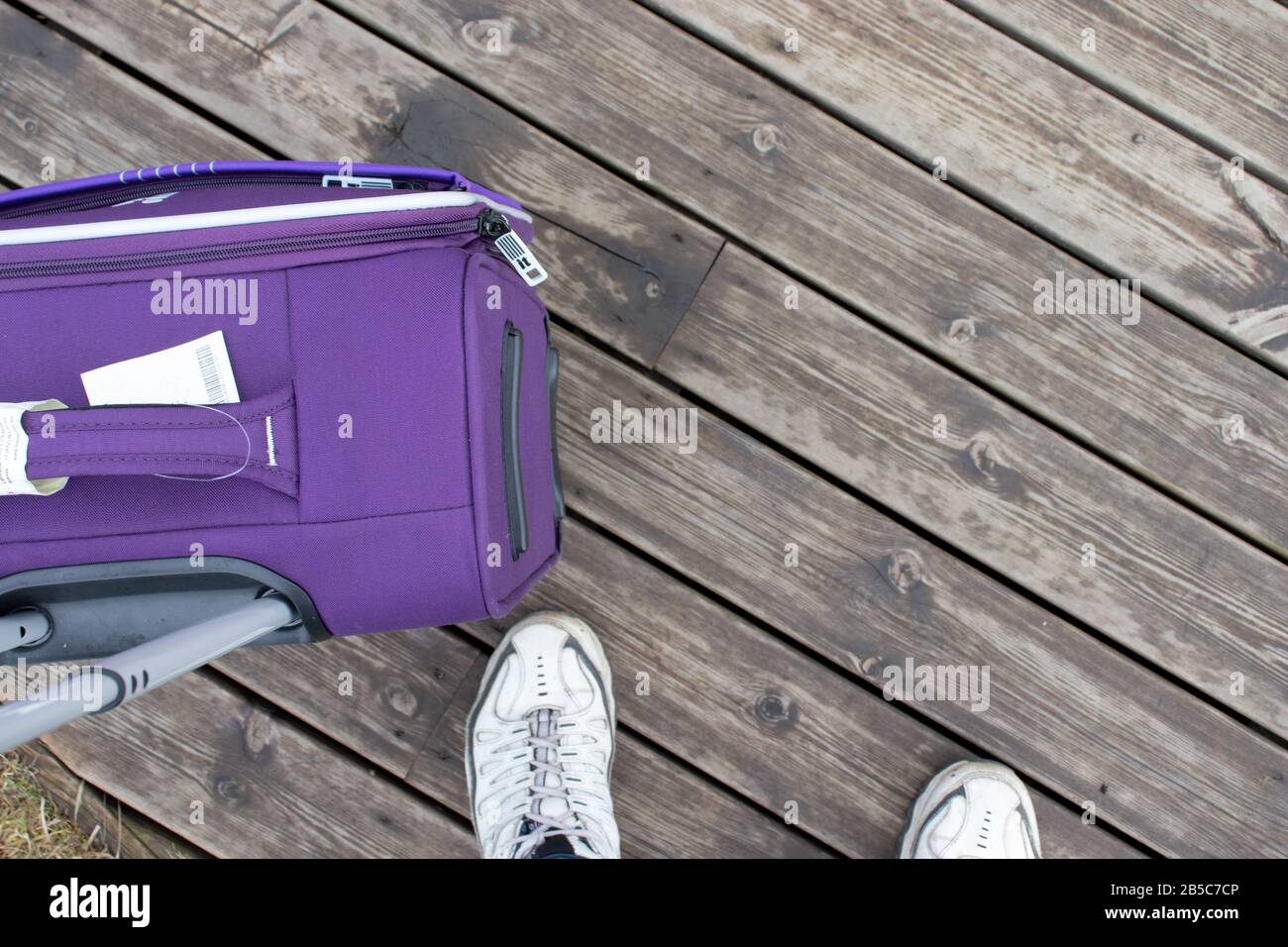 Concept de voyage. Photo du niveau des yeux. Vue sur les jambes et une valise pour le tourisme. Copier l'espace sur la texture du bois Banque D'Images