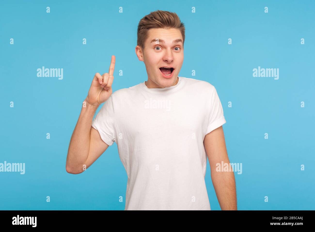 J'en ai une excellente idée ! Portrait de l'homme créatif excité dans un t-shirt blanc décontracté tenant le doigt vers le haut et regardant surpris par la solution soudainement inventée. Banque D'Images