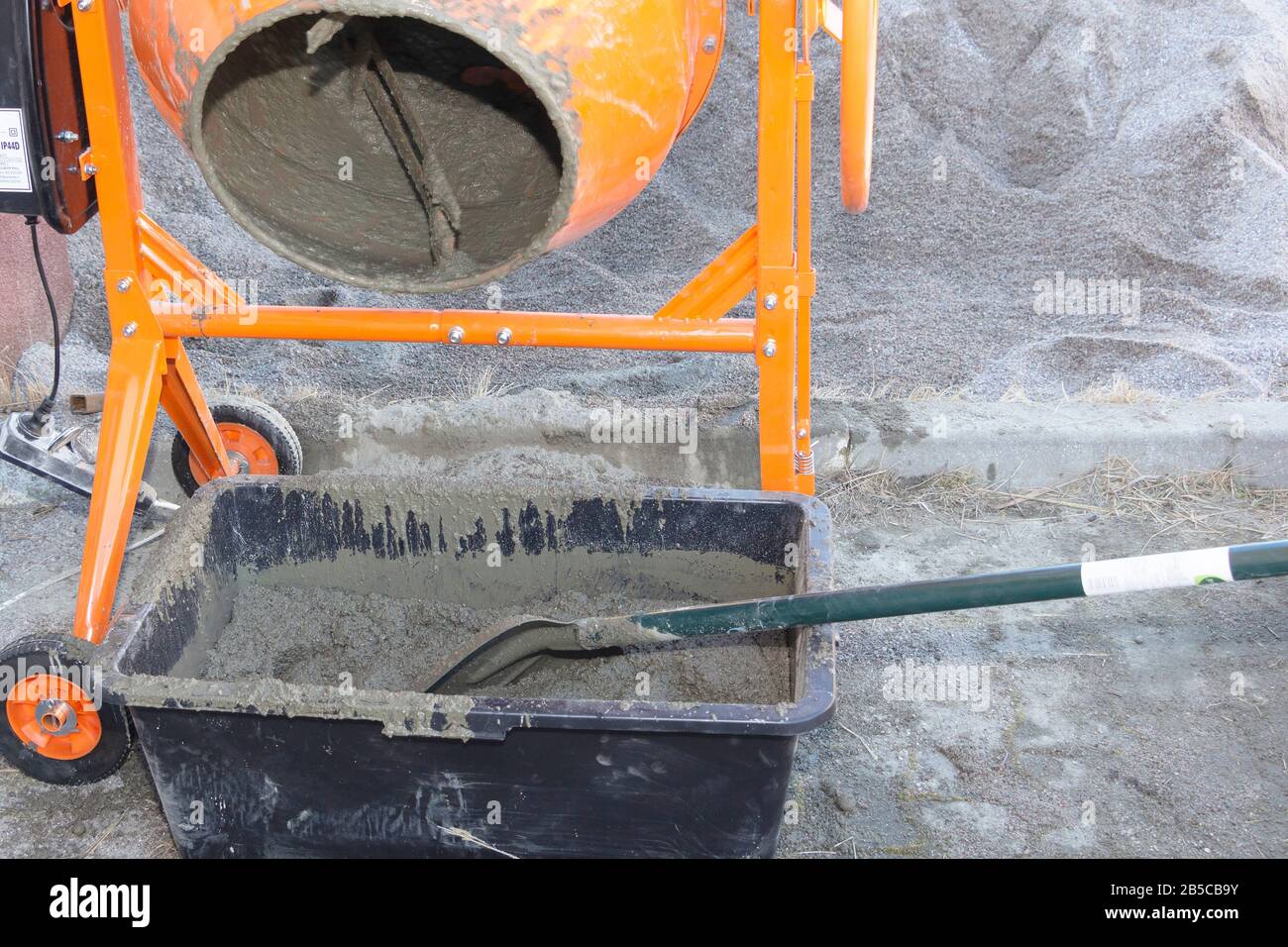 le travailleur de la construction pelle le sable dans le mélangeur de béton. processus de création de ciment sur le site de construction Banque D'Images