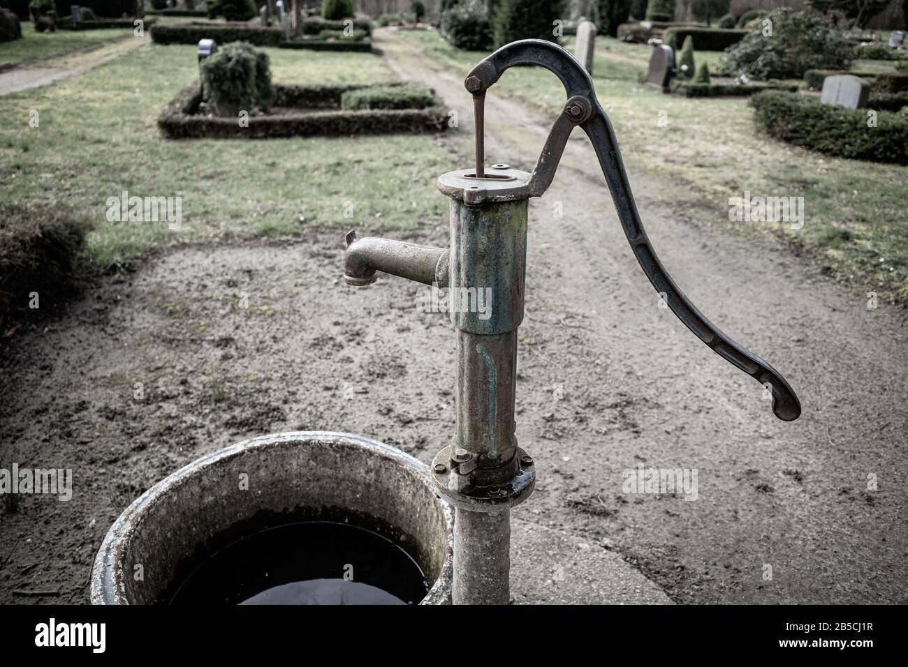 une ancienne pompe à eau en fonte se tient sur un cimetière Photo Stock