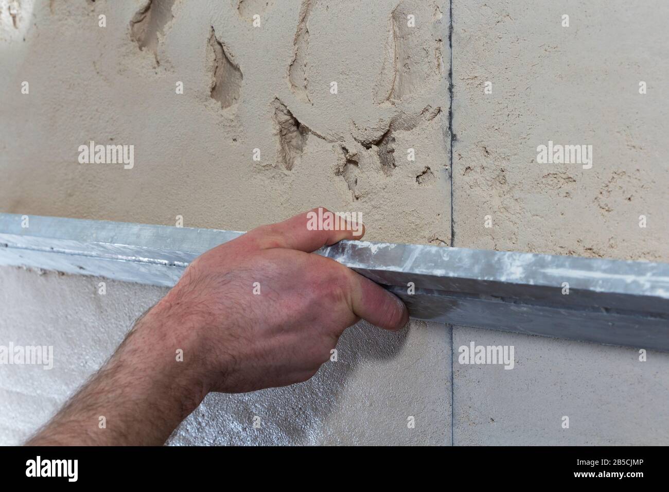 Travailleur de la construction avec une longue spatule pour plâtre le mur à la main Banque D'Images