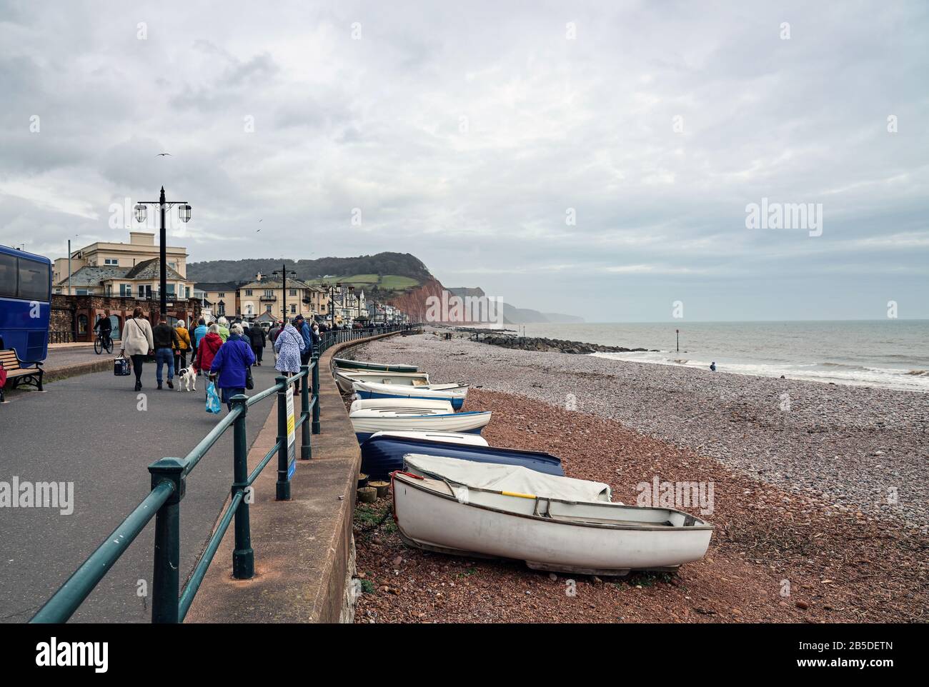 Les daytrippers sont déposés sur le front de mer de Sidmouth pour une visite hors saison. Au loin, la colline de Seaton et la côte jurassique sont en vue Banque D'Images