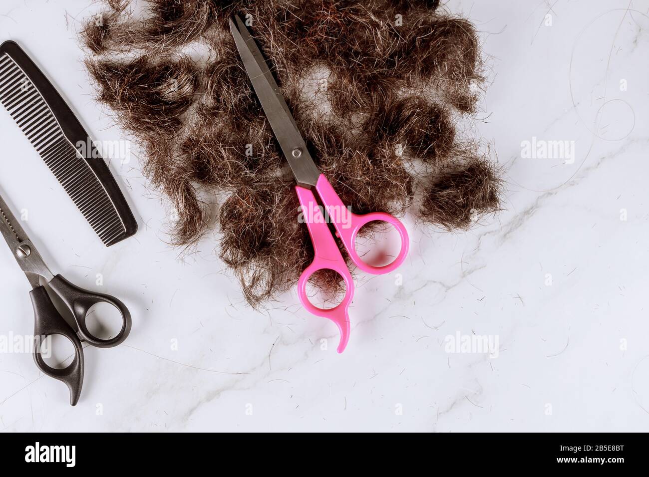 Cheveux coupés en peigne et cheveux de tonte avec ciseaux dans un salon de coiffure Banque D'Images