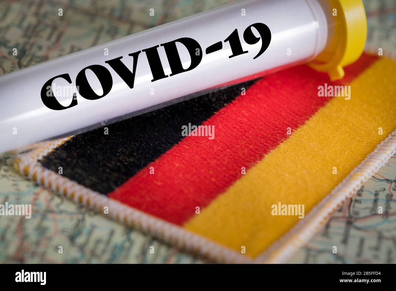 Tube d'essai avec un test positif de coronavirus contre le drapeau allemand Banque D'Images