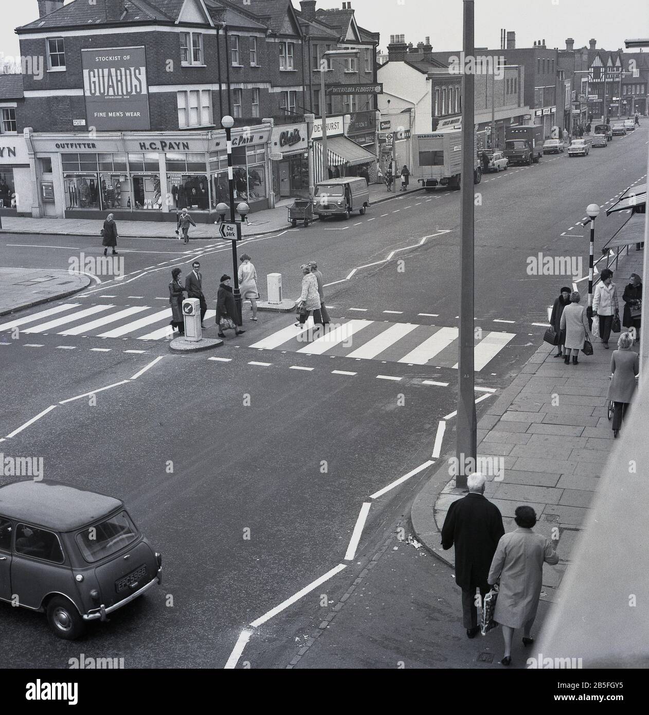 Années 60, historique, Eltham High Street, sud de Londres, les gens traversant la route en utilisant un passage à niveau. Banque D'Images
