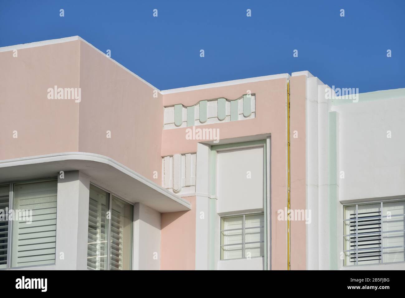 Architecture Art Déco De Miami. Détail mural rose et vert sur la façade de la maison contre ciel bleu clair. Motiffs géométriques et abstraites; couleurs pastel claires et Banque D'Images