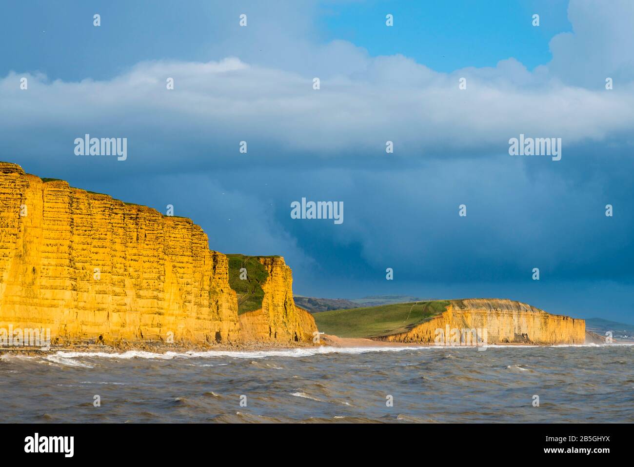 West Bay, Dorset, Royaume-Uni. 8 mars 2020. Météo britannique. Les nuages sombres de la douche traversent les falaises illuminées par le soleil de la fin de l'après-midi à West Bay à Dorset. Crédit Photo : Graham Hunt/Alay Live News Banque D'Images