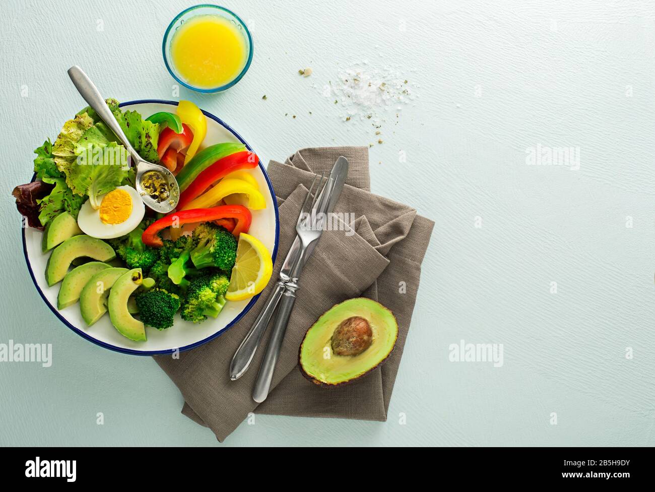 Repas de salade sain avec quinoa, oeuf, avocat et légumes frais mélangés sur fond bleu vue de dessus. Alimentation et santé. Concept de repas sain Banque D'Images