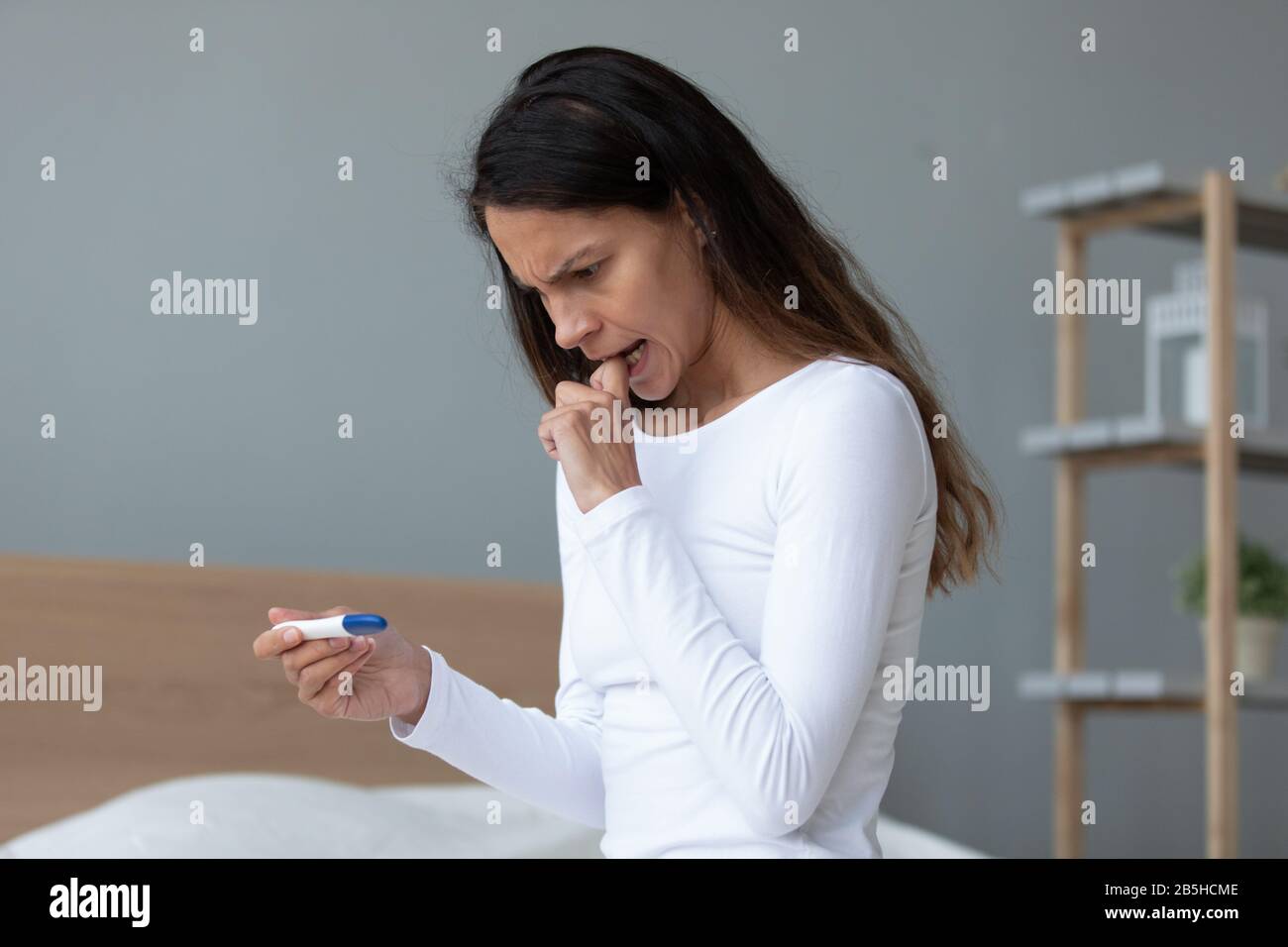 La jeune femme anxieuse regarde les résultats du test de grossesse Banque D'Images