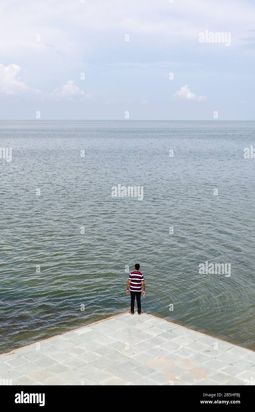 Un seul garçon isolé debout et regardant la vaste étendue du désert blanc submergé en saison de mousson, donnant un sentiment d'échelle. Banque D'Images