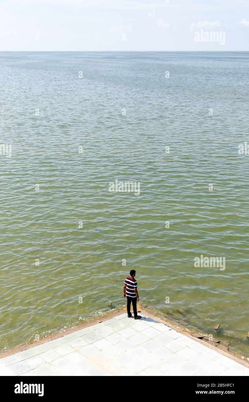 Un seul garçon isolé debout et regardant la vaste étendue du désert blanc submergé en saison de mousson, donnant un sentiment d'échelle. Banque D'Images