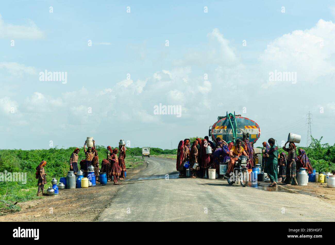 Kutchi femmes remplissant des seaux d'eau d'un camion-citerne garée en travers de la route quelque part à Kutch, Gujarat, Inde Banque D'Images