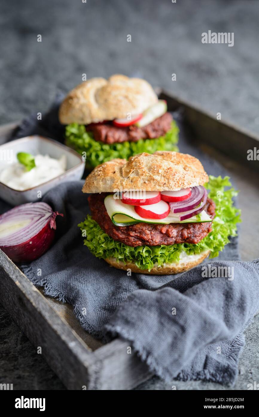 Délicieux hamburger végétarien aux betteraves avec laitue Lollo Bionda, sauce tartare, oignon rouge, courgettes et tranches de radis Banque D'Images
