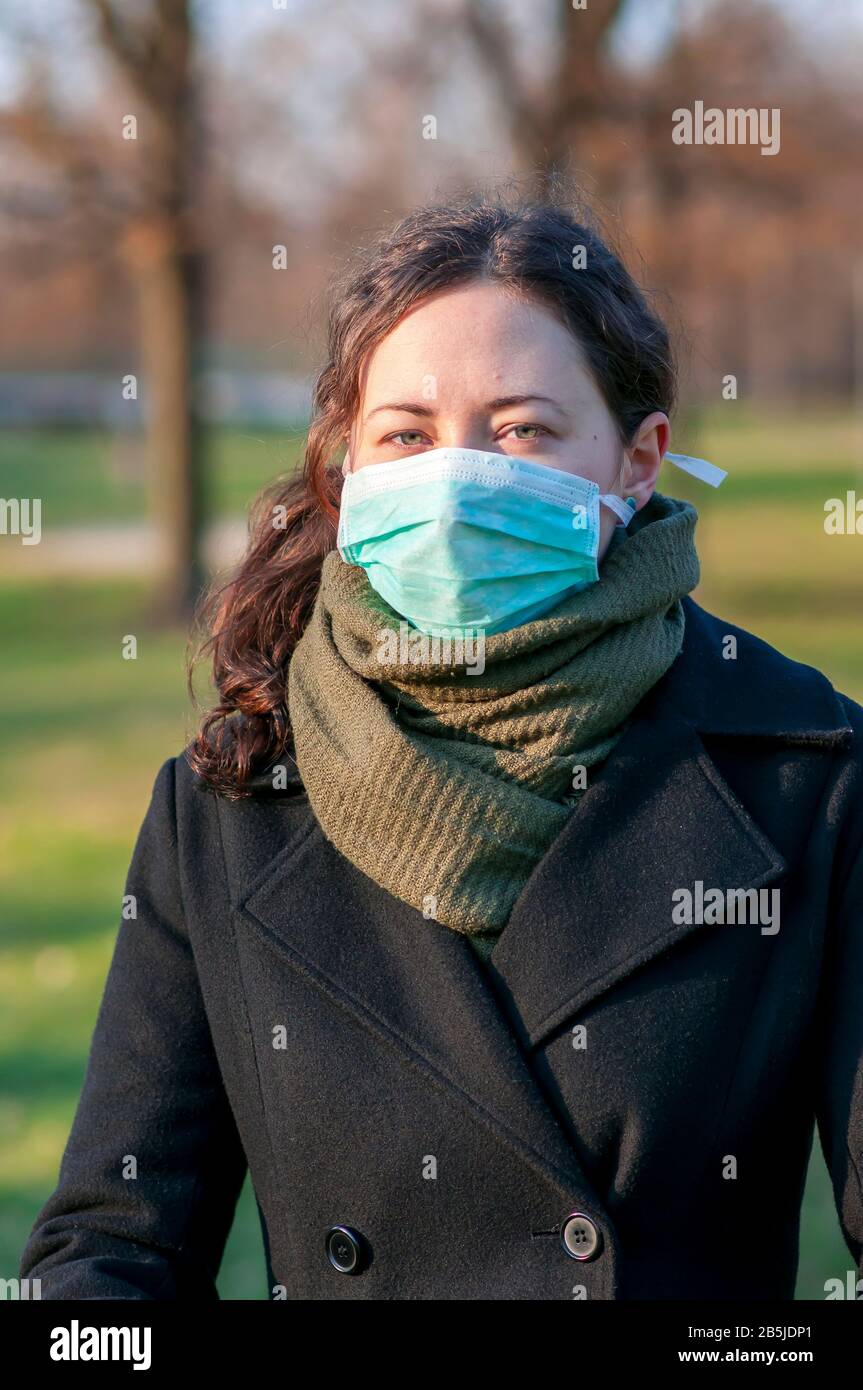 Portrait d'une femme de brunette caucasienne dans un parc en masque médical protecteur sur la protection du visage pour la propagation du virus de la maladie SRAS-COV-2, Coronavirus, C Banque D'Images