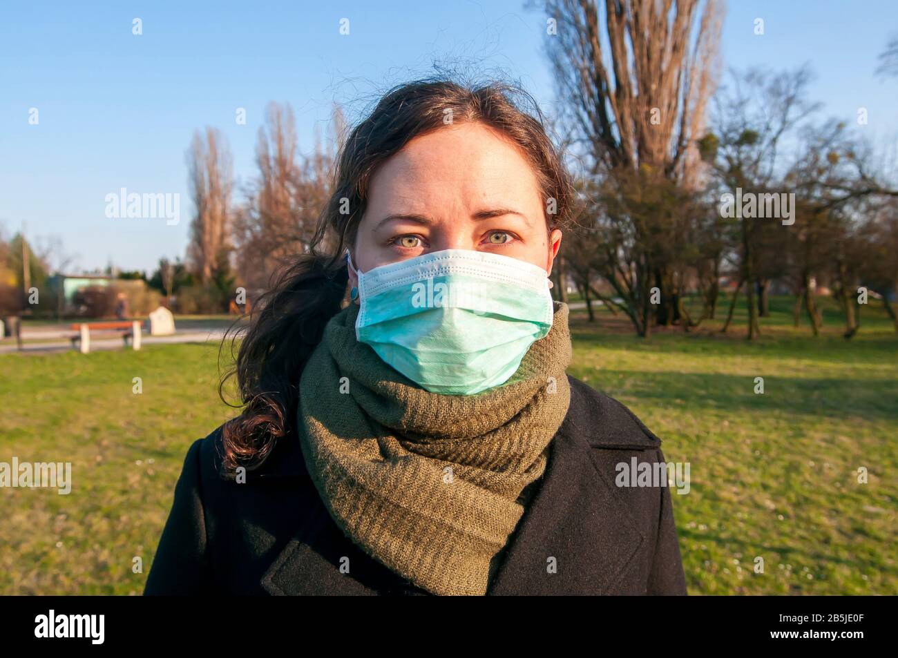Portrait d'une femme de brunette caucasienne dans un parc en masque médical protecteur sur la protection du visage pour la propagation du virus de la maladie SRAS-COV-2, Coronavirus, C Banque D'Images