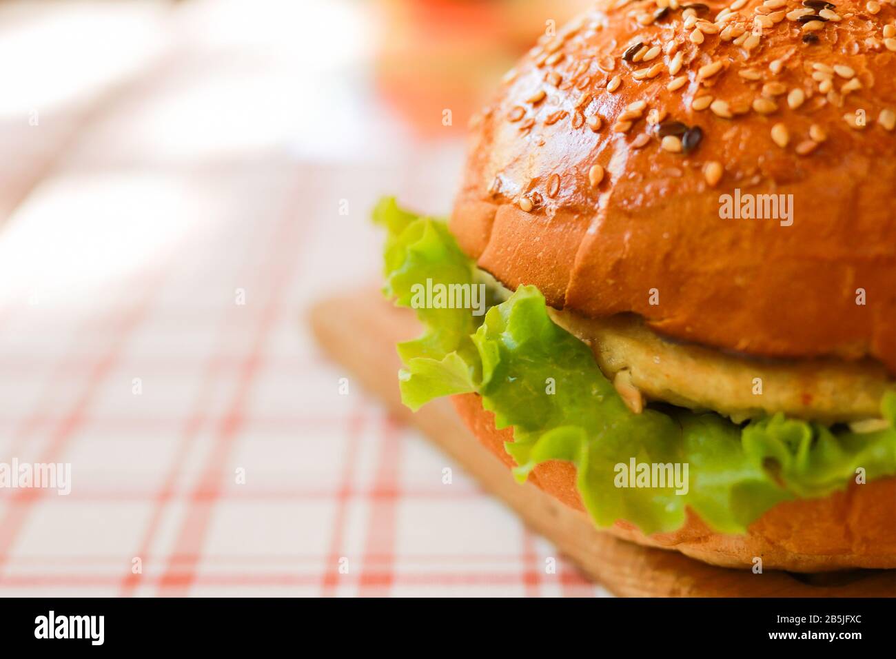 Hamburger végétarien étroit avec graines de sésame, viande artificielle, laitue verte sur la nappe. Mise au point sélectionnée Banque D'Images