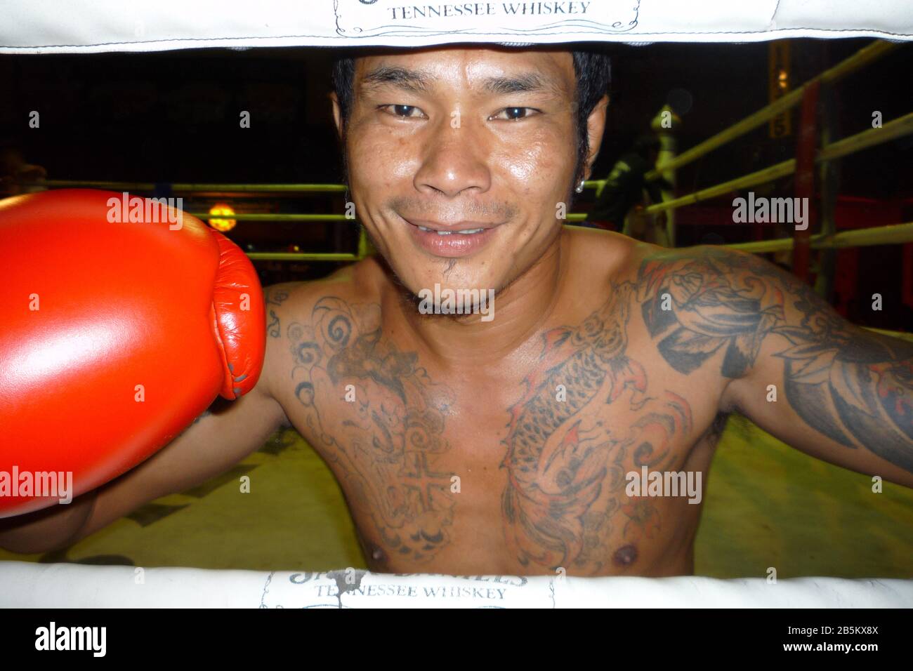 Boxeur de kick thaïlandais asiatique tatoué avec gants de boxe rouge en anneau Banque D'Images