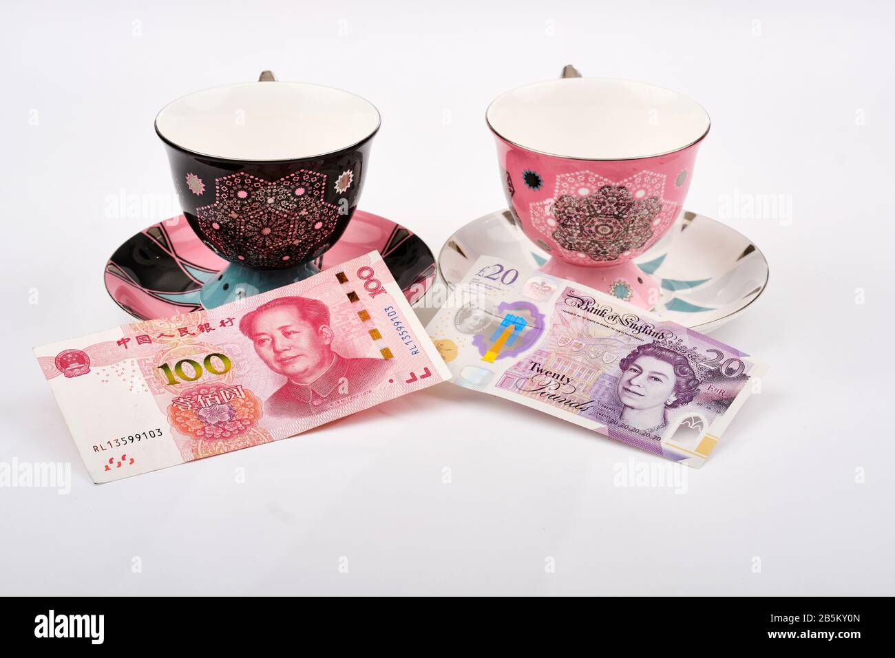 L'est rencontre le concept de voyage ouest avec des tasses à thé décorées avec 20 livres sterling note et 1000 yens note sur les soucoupes Banque D'Images