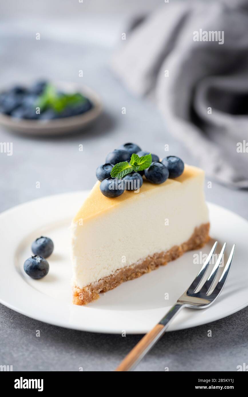 Tranche de Cheesecake avec bleuets frais sur plaque blanche, orientation verticale Banque D'Images