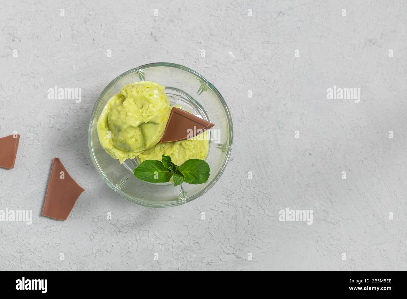 Vue de dessus de la glace d'avocat naturel saine avec feuilles de menthe et morceaux de chocolat sur fond neutre, espace de copie Banque D'Images