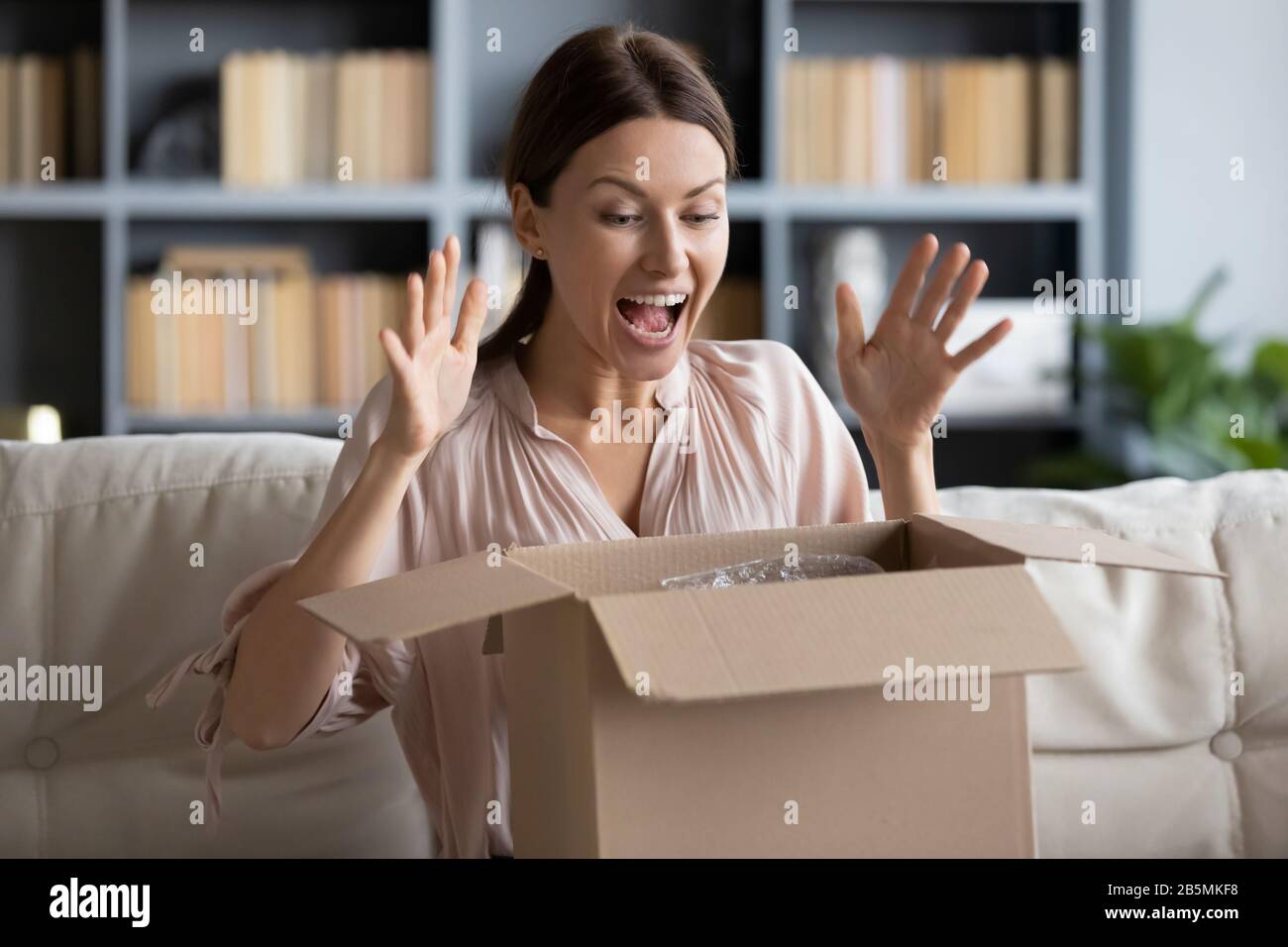 Une jeune cliente heureuse, enchantée par le déballage de l'article souhaité. Banque D'Images
