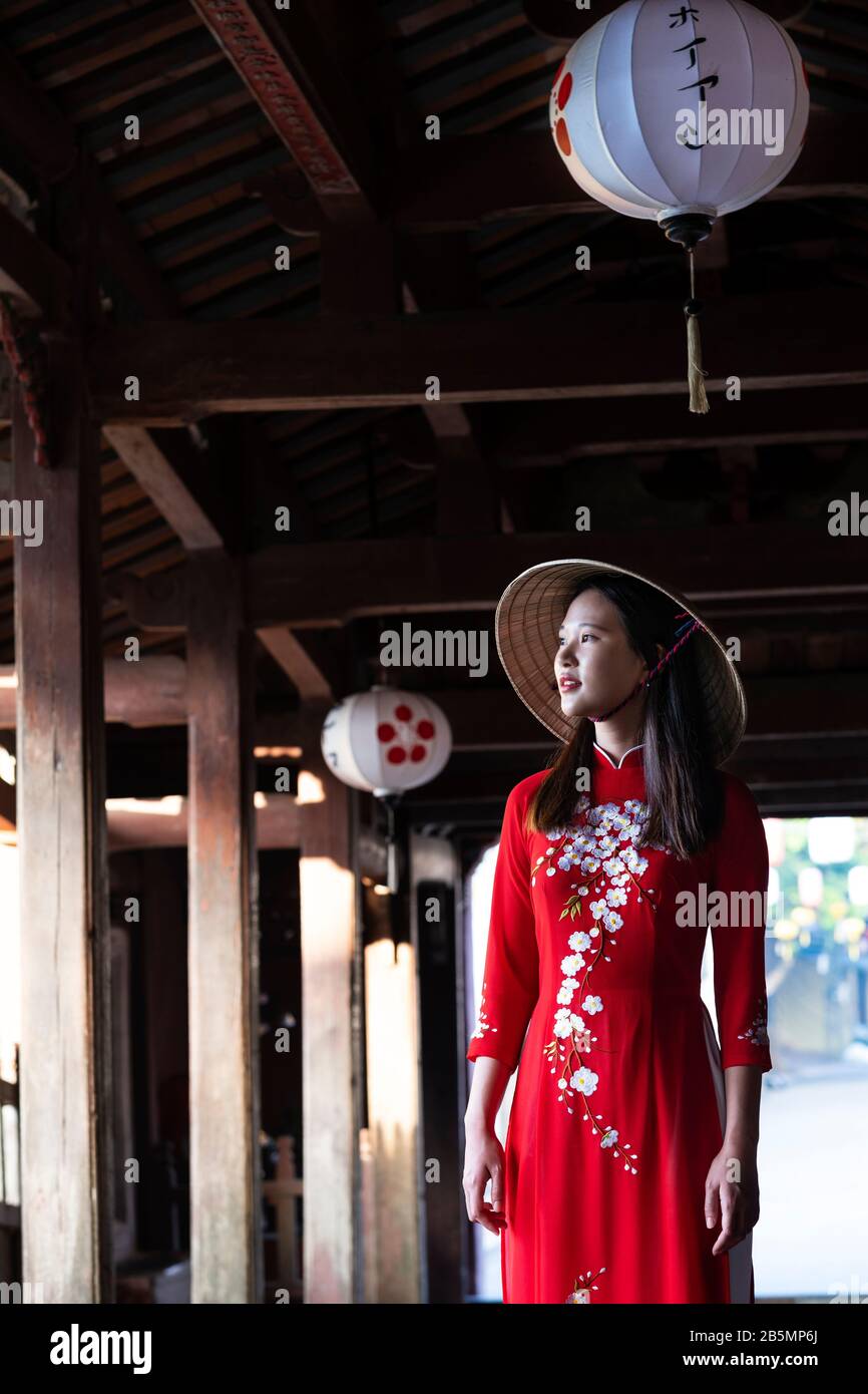 Une jeune femme vietnamienne portant une robe Ao Dai traditionnelle dans les rues de Hoi An, au Vietnam Banque D'Images
