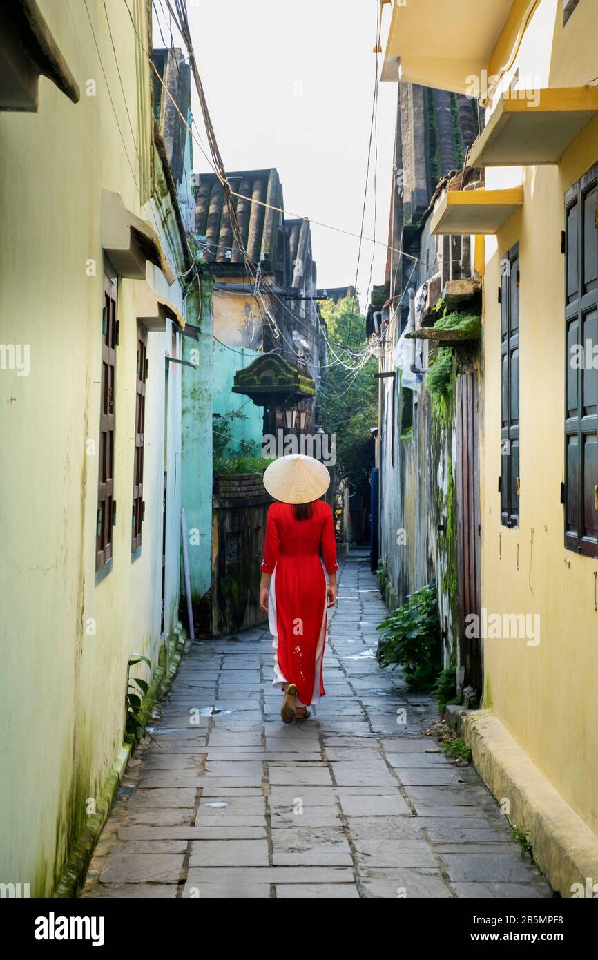 Une jeune femme vietnamienne portant une robe Ao Dai traditionnelle dans les rues de Hoi An, au Vietnam Banque D'Images