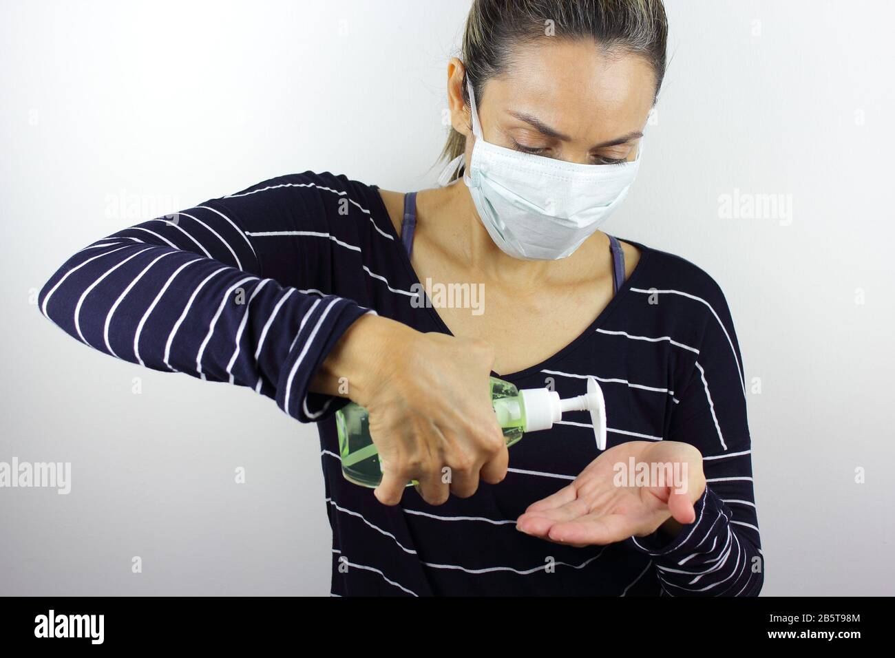 Femme d'Amérique latine portant un masque antivirus avec une bouteille de désinfectant pour les mains Banque D'Images