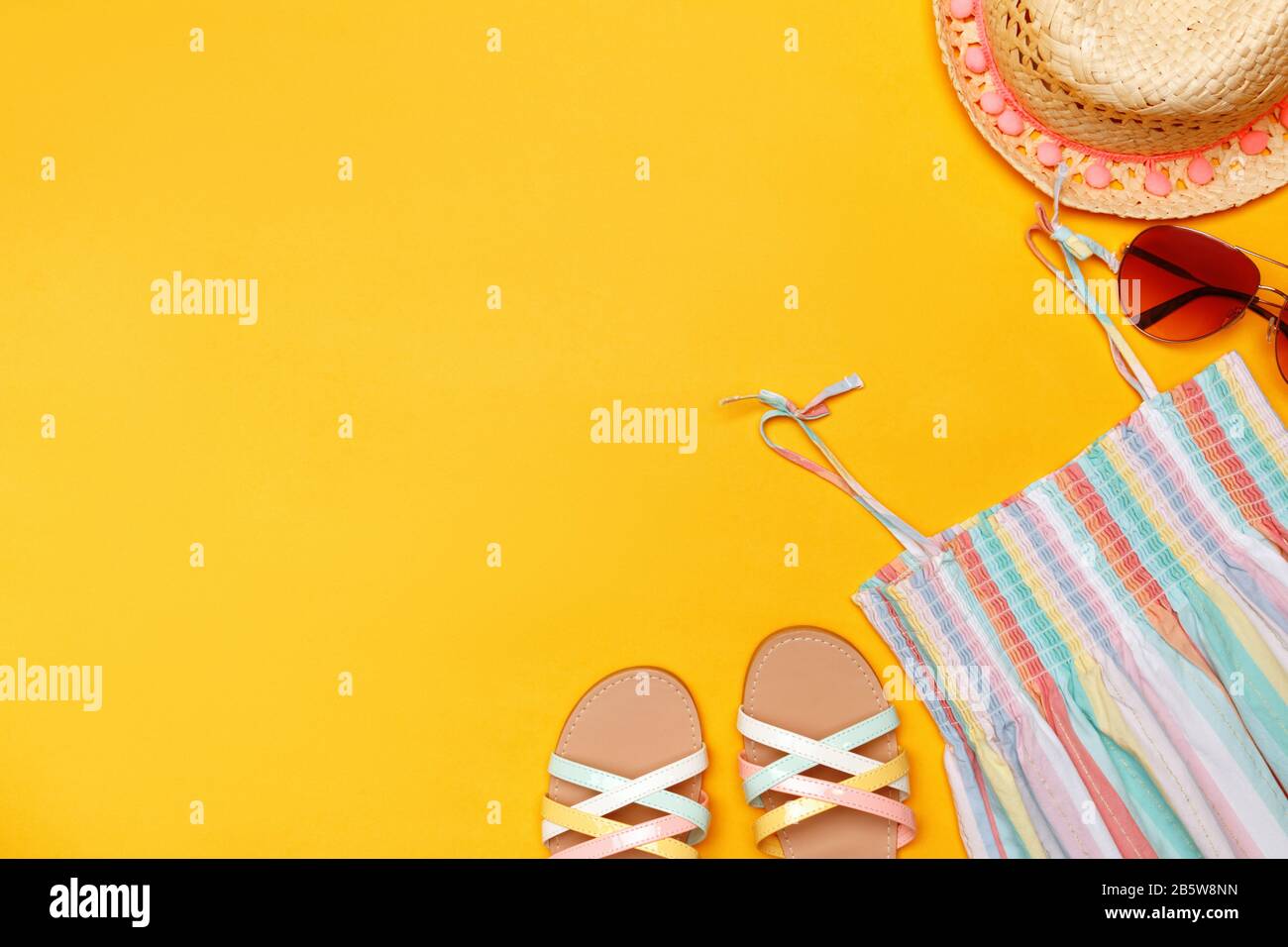 Vêtements d'été sur fond jaune. Lunettes de soleil, sundress, chapeau et sandales. Vue du dessus espace de copie plat. Banque D'Images